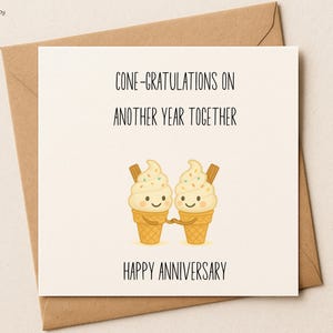 May include: A greeting card with the text "CONE-GRATULATIONS ON ANOTHER YEAR TOGETHER" and "HAPPY ANNIVERSARY". The card features two smiling ice cream cones holding hands. The card is on a brown envelope.