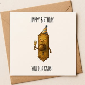 Op de afbeelding: Een verjaardagskaart met een cartoon deurknop karakter met een feesthoedje en een champagneglas. De kaart leest "HAPPY BIRTHAY YOU OLD KNOB!" op een witte achtergrond, met een bruine envelop.