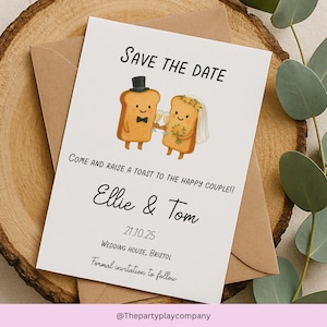 May include: A wedding invitation card with the text "Save the Date" and a cartoon illustration of two toast slices dressed as a bride and groom. The card includes the names "Ellie & Tom" and the date 21.10.25.