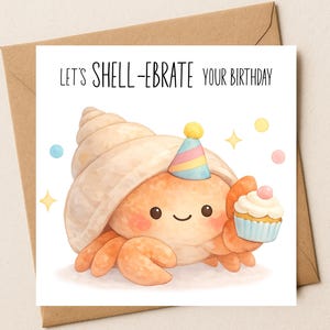 Op de afbeelding: Verjaardagskaart met een aquarel illustratie van een krab met een feesthoedje en een cupcake. De kaart leest "Let's Shell-ebrate Your Birthday" in zwarte tekst. De kaart zit op een bruine envelop.