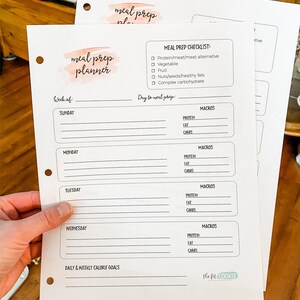 May include: A printable meal prep planner with a watercolor design. The planner includes a checklist for meal prep, a section for daily and weekly calorie goals, and a section for tracking macros for each day of the week. The planner is titled "meal prep planner" and "The Fit Cookie" is printed at the bottom.