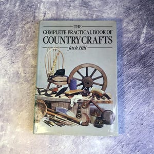 May include: The Complete Practical Book of Country Crafts by Jack Hill. The book cover features a vintage illustration of a wooden wheel, a chair, and various tools.
