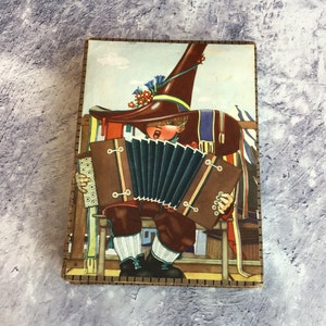 Caja de bombones decorativa vintage con imagen de un niño holandés tocando el acordeón
