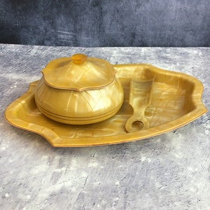 May include: A yellow, oval-shaped tray with a matching yellow lidded bowl and a small scoop. The tray and bowl have a marbled, iridescent finish.