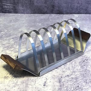 Rejilla para tostadas de acero inoxidable de estilo modernista vintage de la marca Castle con bandeja recogemigas deslizante y asas de madera, soporte retro para 6 rebanadas.