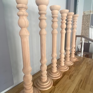 May include: Five wooden candle holders with a fluted design and a rounded top. The candle holders are arranged in a row on a wooden surface.