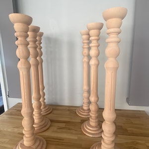 May include: Six wooden candle holders with a fluted design and a round base. The candle holders are made of natural wood and have a light brown color.