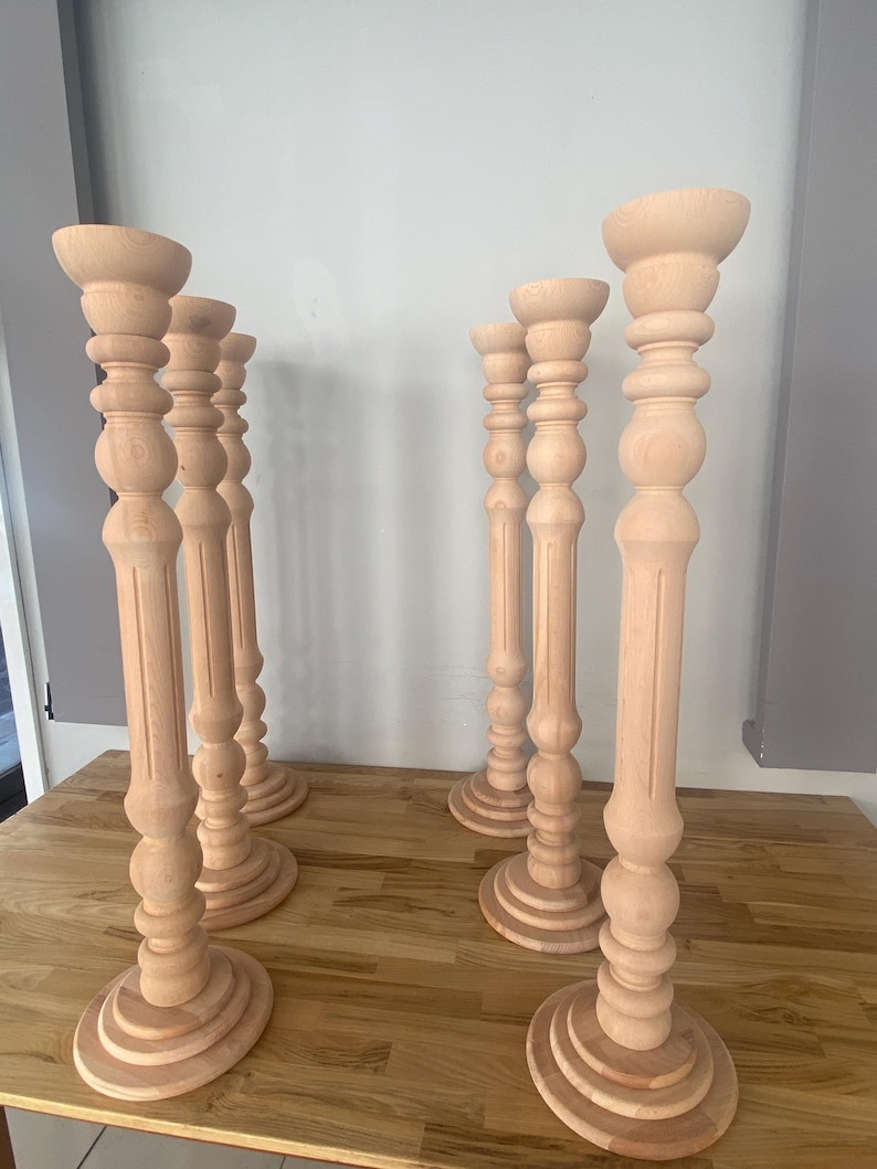 May include: Six wooden candle holders with a fluted design and a round base. The candle holders are made of natural wood and have a light brown color.