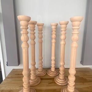 May include: Set of six wooden candle holders with a turned design. The candle holders are all the same height and have a round base.