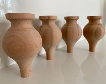 May include: Four unfinished wooden furniture legs with a bulbous, rounded shape. The legs are made of light-colored wood and have a smooth, polished finish.