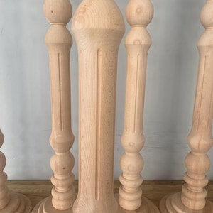 May include: Four unfinished wooden table legs with a turned design. Each leg has a rounded base and a series of decorative balls.