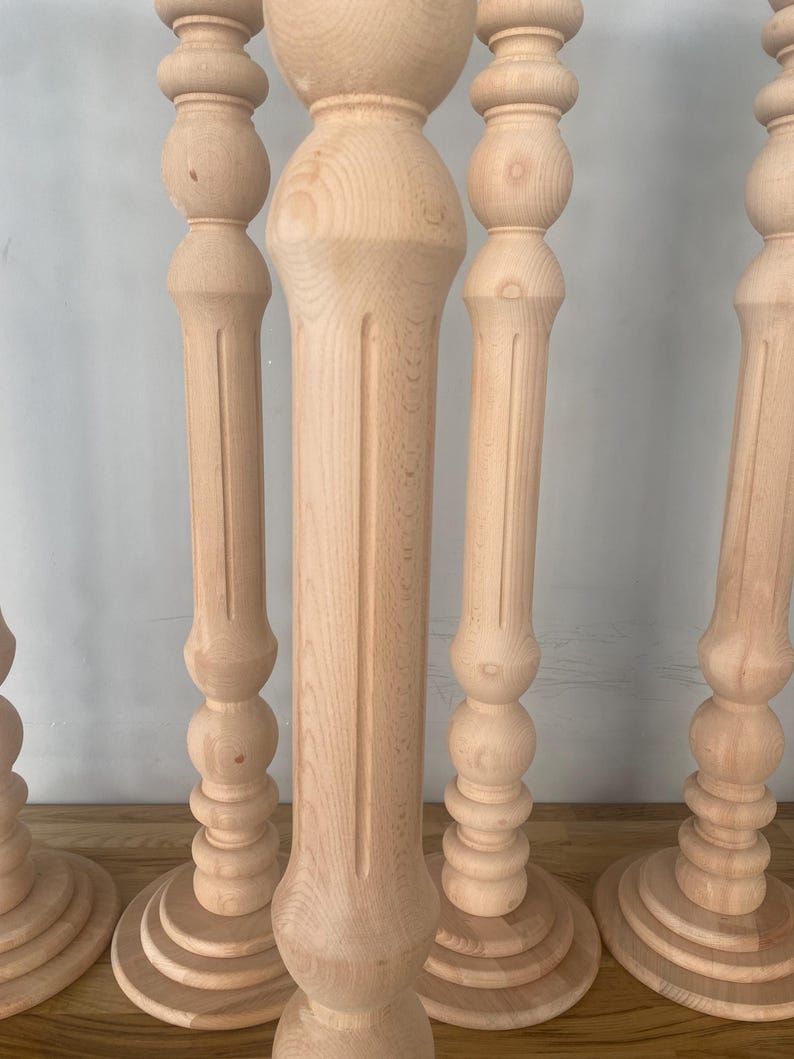 May include: Four unfinished wooden table legs with a turned design. Each leg has a rounded base and a series of decorative balls.