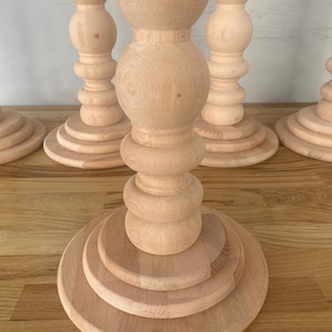 May include: Four wooden table legs with a rounded, bulbous design. The legs are made of light-colored wood and have a smooth finish.