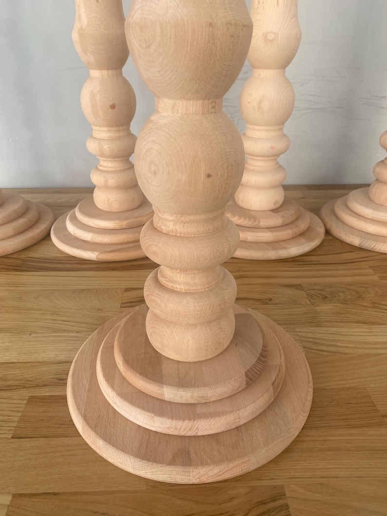 May include: Four wooden table legs with a rounded, bulbous design. The legs are made of light-colored wood and have a smooth finish.