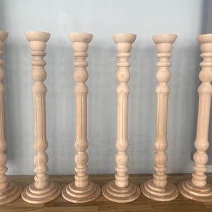 May include: Set of seven wooden candle holders with a fluted design. The candle holders are all the same size and shape, and they are made of a light-colored wood.