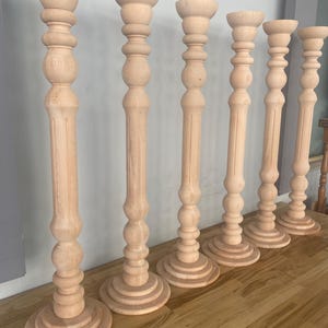May include: Six wooden candle holders with a turned design. The candle holders are all the same style, but vary in height. They are made of natural wood and have a smooth finish.