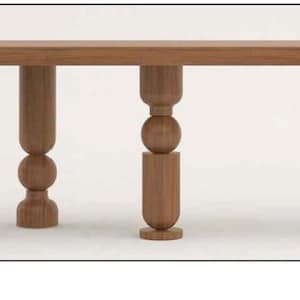 May include: A long, rectangular wooden table with four unique, turned wooden legs. Each leg features a different design with multiple rounded sections.
