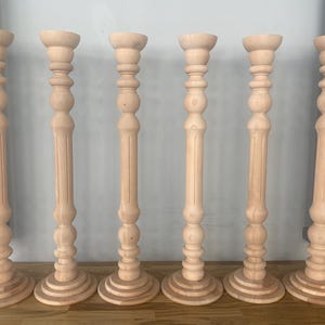 May include: Six wooden candle holders with a fluted design and a round base. The candle holders are all the same size and are arranged in a row.