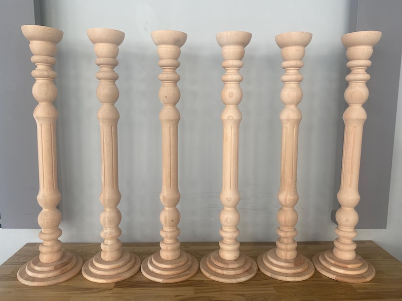May include: Six wooden candle holders with a fluted design and a round base. The candle holders are all the same size and are arranged in a row.