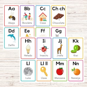 Può includere: Flashcards colorate con l'alfabeto spagnolo. Ogni carta presenta una lettera, un'immagine e la parola spagnola per l'immagine. Le lettere sono Aa, Bb, Cc, Ch ch, Dd, Ee, Ff, Gg, Hh, Ii, Jj, Kk, Ll, Ll II, Mm e Nn. Le immagini includono un'ape, una bicicletta, una casa, cioccolato, un delfino, una stella, un fiore, un gatto, gelato, una coccinella, una giraffa, un kiwi, la luna, una chiave, una mela e un'arancia.