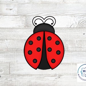 May include: Red and black ladybug cookie cutter with white antennae. The cutter is on a white wood background.