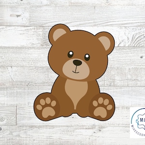 Puede incluir: Cortador de galletas de oso marrón con un diseño simple. El oso está sentado con sus patas delante de él.