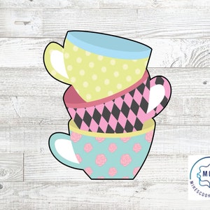 May include: A stack of three teacups with different patterns. The top cup is yellow with white polka dots, the middle cup is pink with black diamonds, and the bottom cup is blue with white flowers.