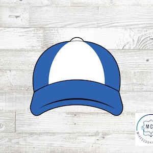 Könnte beinhalten: Ein Keksausstecher in Form einer blauen und weißen Baseballkappe. Die Kappe hat ein weißes Frontpanel und einen blauen Schirm.