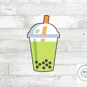 May include: A green and white cookie cutter shaped like a boba tea with a straw. The boba tea has black boba pearls inside.