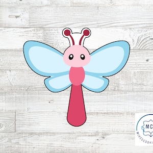 May include: A cartoon butterfly cookie cutter. The cutter features a pink body, light blue wings, and a red antenna. The butterfly has a smiling face with black eyes. The cutter is designed for baking and crafting.