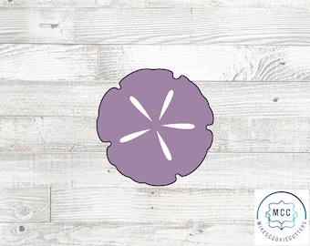 May include: A lavender-colored sand dollar cookie cutter with white radial lines. The cutter is made of metal and has a black outline. The background is a light wood grain pattern. The logo for MikesCookieCutters is in the lower right corner.