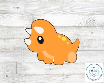 May include: Orange cartoon triceratops cookie cutter with a white background.