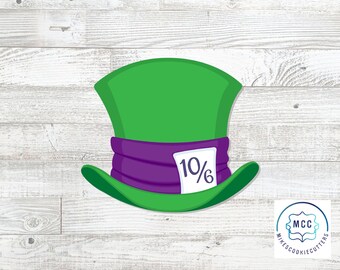 May include: A green top hat cookie cutter with a purple band and a white tag featuring the text 10/6. The design is shaped like a tall hat with a wide brim, featuring a vibrant green crown and a dark purple ribbon wrapped around the base.