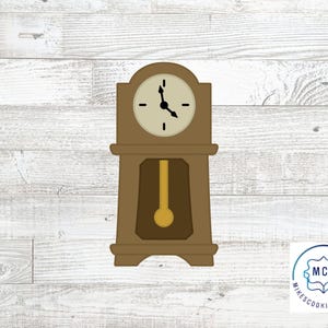 Może przedstawiać: Brązowa foremka do ciastek w kształcie zegara stojącego. Zegar ma okrągłą tarczę z czarnymi wskazówkami i wahadłem. Foremka do ciastek jest wykonana z metalu i ma za zadanie wyciąć kształt klasycznego zegara stojącego.