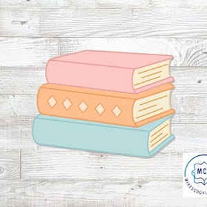 May include: A cookie cutter shaped like a stack of three books. The top book is pink, the middle book is orange with a diamond pattern, and the bottom book is light blue. The logo in the corner reads MCC MIKESCOOKIECUTTERS.