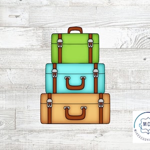 May include: Three stacked vintage suitcases with brown leather straps and metal buckles. The top suitcase is green, the middle suitcase is blue, and the bottom suitcase is brown.  The suitcases are on a white wood background.