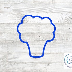 May include: Blue plastic cookie cutter shaped like a head of broccoli on a white wood background. The cookie cutter is for making cookies, fondant, or other edible crafts.
