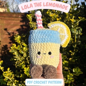 May include: A crochet lemonade plushie with a yellow and blue body, a pink and white striped straw, and a lemon slice. The text "Lola the Lemonade" is displayed on the top. The plushie has brown feet. The image also includes the text "PDF Crochet Pattern".