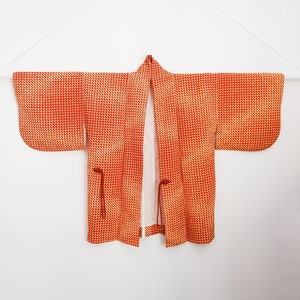May include: A red and yellow patterned kimono with a white lining. The kimono has a traditional Japanese design and is made of a lightweight fabric.