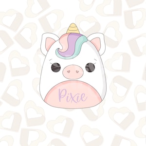 Op de afbeelding: Een wit pluche unicorn speelgoed met een roze neus, paarse en blauwe manen en een gele hoorn. Het speelgoed heeft een roze buik met het woord "Pixie" in paars geschreven.