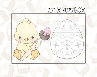 May include: A yellow chick holding a paintbrush with pink and brown paint, next to an Easter egg outline. The box is 7.5" x 4.25". The egg has a decorative design with hearts and swirls. The chick is sitting down.