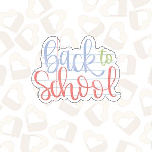 Puede incluir: Un cortador de galletas en forma de nube con la frase "Back to School" escrita en una fuente colorida. El texto es azul, verde y rojo, sobre un fondo de papel rayado.