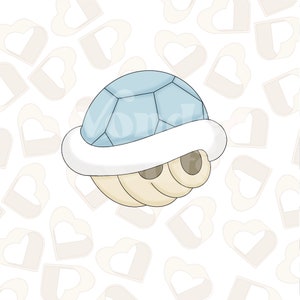 May include: A blue and white cartoon shell with a white rim. The shell is on a white background with a pattern of light brown hearts.