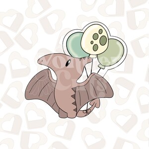 Peut inclure: Un ptérodactyle de dessin animé avec des ailes brunes et un corps brun clair tient trois ballons. Les ballons sont verts, jaunes avec des taches brunes et verts.