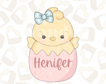 May include: A pink and white egg with a yellow chick inside. The chick has a blue bow and the egg says "Henifer".
