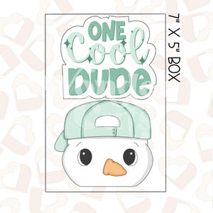May include: A white snowman cookie cutter with a green baseball cap and the text "One Cool Dude" above it. The cookie cutter is 7 inches by 5 inches.