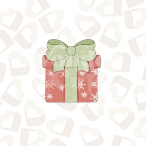 May include: A red gift box with a green bow and white snowflake pattern. The box is on a white background with a pattern of white hearts.