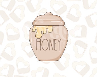 Może przedstawiać: Beige ceramiczny słoik na miód z pokrywką i motywem kapania miodu. Słoik ma napis "HONEY" na przodzie.
