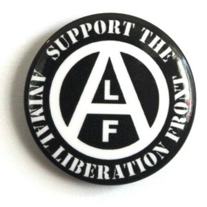May include: Black and white button with the text "Support the Animal Liberation Front" surrounding a white anarchy symbol with the letters "L" and "F" inside.