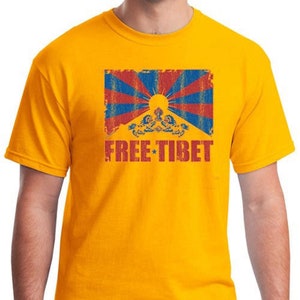Pu&ograve; includere: Una maglietta gialla con un'immagine usurata della bandiera tibetana e il testo "FREE TIBET" in rosso.